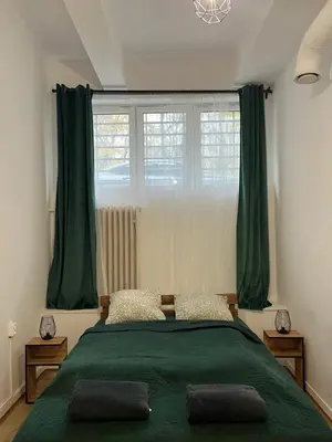 a bedroom with a green bed and a window at TomTom Hostel in Kraków