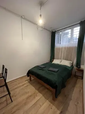 a bedroom with a green bed and a window at TomTom Hostel in Kraków