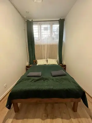 a bedroom with a large bed with a green blanket at TomTom Hostel in Kraków