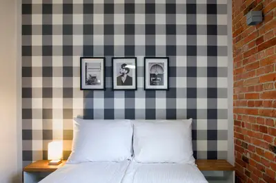 a bedroom with a checkered wall with three pictures above a bed at Discover Krakow Apartments - Lubicz St - Loft - Next to Main Station, AC in Kraków