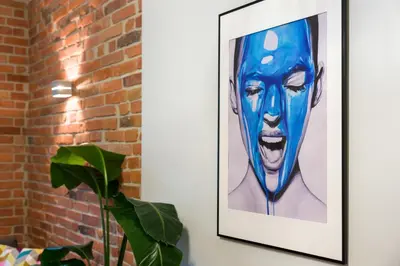 a painting of a man on a wall next to a plant at Discover Krakow Apartments - Lubicz St - Loft - Next to Main Station, AC in Kraków