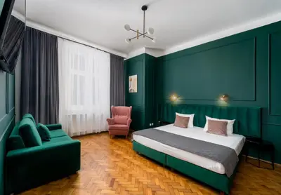 a bedroom with green walls and a bed and a chair at Wawel Apartments - Old Town in Kraków