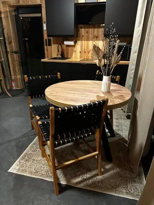 a wooden table with two chairs and a vase with flowers at Brown Deer - z Sauną na Tarasie, Jacuzzi i Widokiem na Góry - by Deer Hills Luxury Apartments in Kocoń