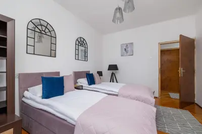 two beds in a room with white walls and blue pillows at Rodzinny Apartament z dwiema sypialniami niedaleko centrum Krakowa by Noclegi Renters in Kraków