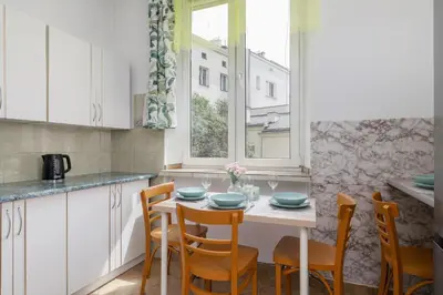a kitchen with a table with chairs and a window at Rodzinny Apartament z dwiema sypialniami niedaleko centrum Krakowa by Noclegi Renters in Kraków