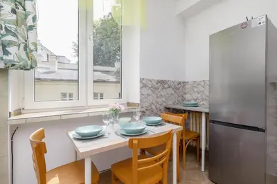 a kitchen with a table with chairs and a refrigerator at Rodzinny Apartament z dwiema sypialniami niedaleko centrum Krakowa by Noclegi Renters in Kraków