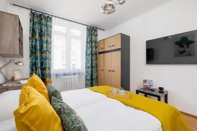 a bedroom with a white bed and a yellow blanket at Rodzinny Apartament z dwiema sypialniami niedaleko centrum Krakowa by Noclegi Renters in Kraków