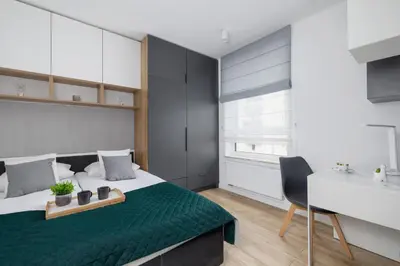 a bedroom with a bed with a green blanket and a desk at Elegant Apartment in Cracow with Balcony, Parking and Desk by Noclegi Renters in Kraków