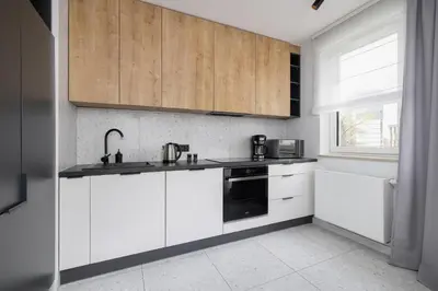 a kitchen with white cabinets and a sink and a window at Elegant Apartment in Cracow with Balcony, Parking and Desk by Noclegi Renters in Kraków