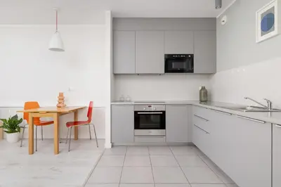 a kitchen with white cabinets and a table and a dining room at 1 bedroom Apartment with Terrace - Wawrzyńca 21 in Kraków