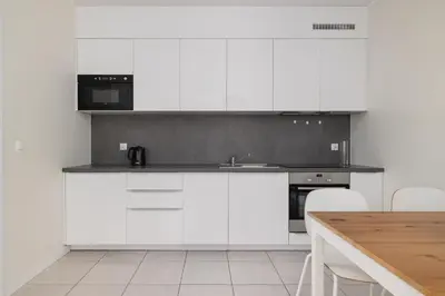 a kitchen with white cabinets and a wooden table at Apartment with Terrace - Wawrzyńca 21 Street in Kraków