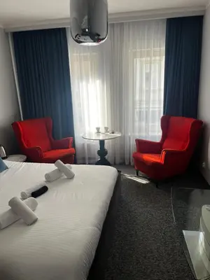a hotel room with two beds and two red chairs at Sweet Dreams Apartments Kazimierz in Kraków
