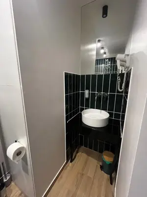 a bathroom with a sink and a black tiled wall at Sweet Dreams Apartments Kazimierz in Kraków