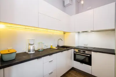 a kitchen with white cabinets and a counter top at Krowoderska Residence WAWELOFTS in Kraków