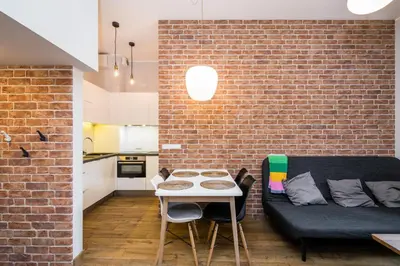 a room with a table and a couch and a brick wall at Krowoderska Residence WAWELOFTS in Kraków