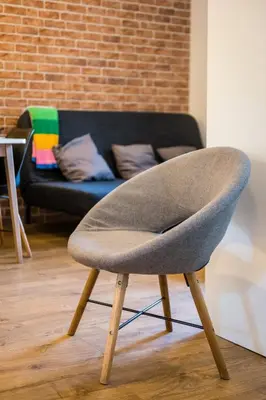 a grey chair in a living room with a couch at Krowoderska Residence WAWELOFTS in Kraków