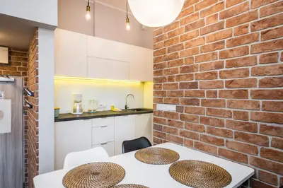 a kitchen and dining room with a brick wall at Krowoderska Residence WAWELOFTS in Kraków