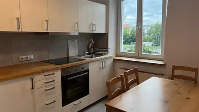 a kitchen with white cabinets and a table with chairs at P&J Apartments Koletek in Kraków