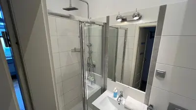 a bathroom with a shower and a sink and a mirror at P&J Apartments Koletek in Kraków