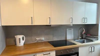 a kitchen with white cabinets and a sink at P&J Apartments Koletek in Kraków