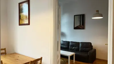 a living room with a black leather couch and a table at P&J Apartments Koletek in Kraków