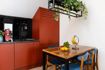 a kitchen with red cabinets and a wooden table with fruit at Horizon Apartments - Luxury Studio, Old Town in Kraków