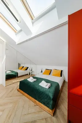 a bedroom with a large bed with green sheets and orange pillows at Horizon Apartments - Luxury Studio, Old Town in Kraków