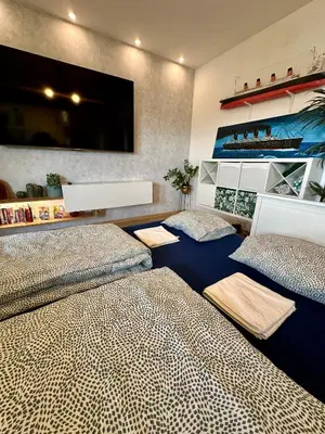 a bedroom with two beds and a tv on the wall at Kaczary Deluxe 56m2 in Kraków