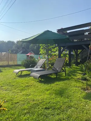 two lounge chairs and an umbrella in the grass at Apartament Koszarawa in Koszarawa