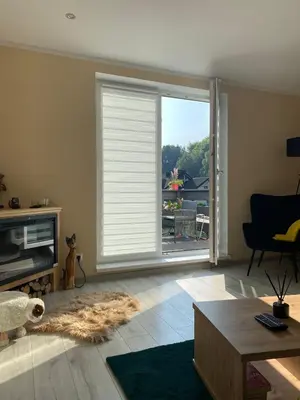 a living room with a large window with blinds at Apartament Koszarawa in Koszarawa