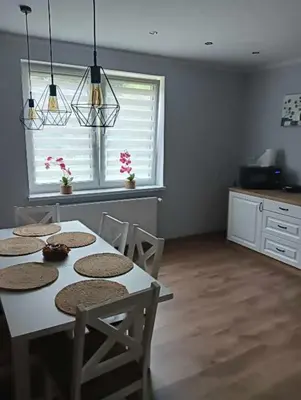 a dining room with a table and chairs and a kitchen at Apartament Koszarawa in Koszarawa