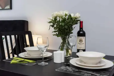a table with a bottle of wine and a vase of flowers at Malila Premium Apartaments Cracow City Center Rtm Zbigniewa Dunin Wąsowicza 3 in Kraków
