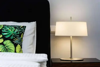 a lamp sitting on a table next to a bed at Malila Premium Apartaments Cracow City Center Rtm Zbigniewa Dunin Wąsowicza 3 in Kraków