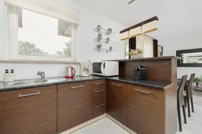 a kitchen with wooden cabinets and a sink at Przestronny Apartament w Krakowie z Biurkiem, Parkingiem i Wanną by Noclegi Renters in Kraków