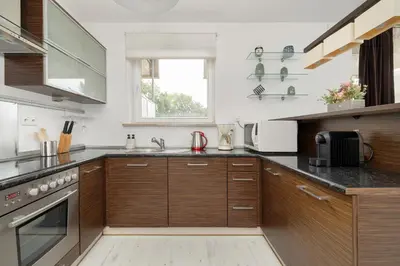 a large kitchen with wooden cabinets and a sink at Przestronny Apartament w Krakowie z Biurkiem, Parkingiem i Wanną by Noclegi Renters in Kraków