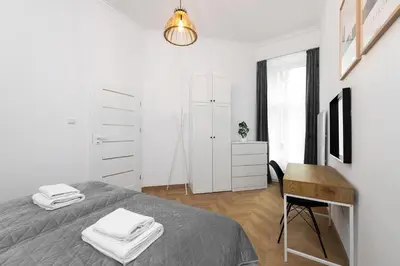 a white bedroom with a bed and a desk at Apartament Sarego Krakow Center in Kraków