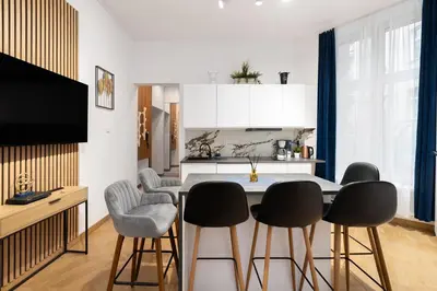 a kitchen with a table with chairs and a kitchen with white cabinets at Apartament Sarego Krakow Center in Kraków