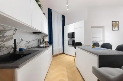 a kitchen with white cabinets and a black sink at Apartament Sarego Krakow Center in Kraków