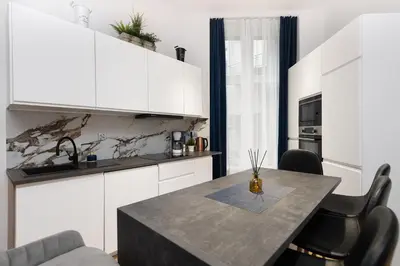 a kitchen with white cabinets and a table with chairs at Apartament Sarego Krakow Center in Kraków