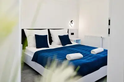 a bed with blue and white sheets and pillows at Zatorski Apartament na Jaśminowej in Zator