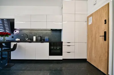 a kitchen with white cabinets and a wooden door at Zatorski Apartament na Jaśminowej in Zator