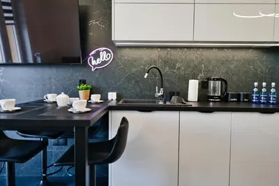a kitchen with white cabinets and a black table at Zatorski Apartament na Jaśminowej in Zator