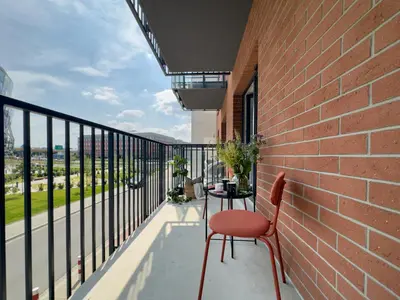 a balcony with a red chair and a table at Klimeckiego Luxury Apartments 189 in Kraków