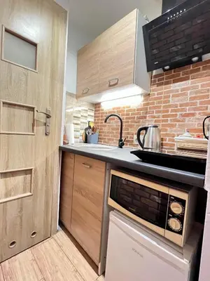 a kitchen with wooden cabinets and a brick wall at Antique apartment in Krakow in Kraków