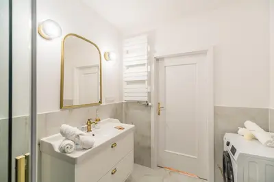 a white bathroom with a sink and a mirror at Kraków Libra Apartment - AC - by Rentujemy in Kraków