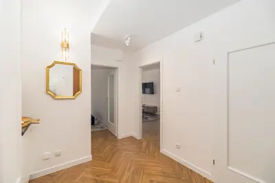 a hallway with white walls and wood floors and a mirror at Kraków Libra Apartment - AC - by Rentujemy in Kraków