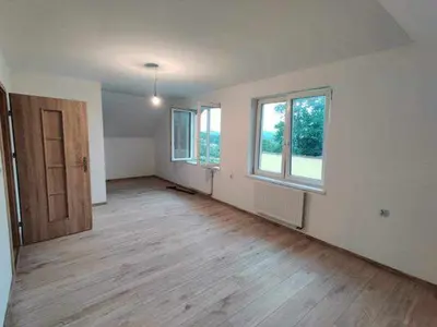 an empty living room with a wooden floor and windows at Świnna Poręba Rooms in Świnna Poręba