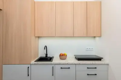 a kitchen with white cabinets and a sink and a bowl of fruit at Smart Studio 5 in Kraków