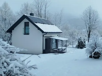a small white house with snow on the ground at Domek Całoroczny in Stróża