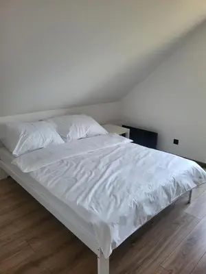 a bedroom with a white bed with white sheets at Domek Całoroczny in Stróża